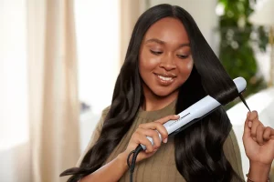 Philips BHS520/00 Hair Straightener in Use Woman styling a section of long dark hair with a pale blue Philips hair straightener