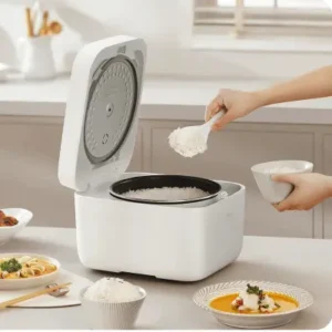 Person serving cooked white rice into a bowl from an open white electric rice cooker