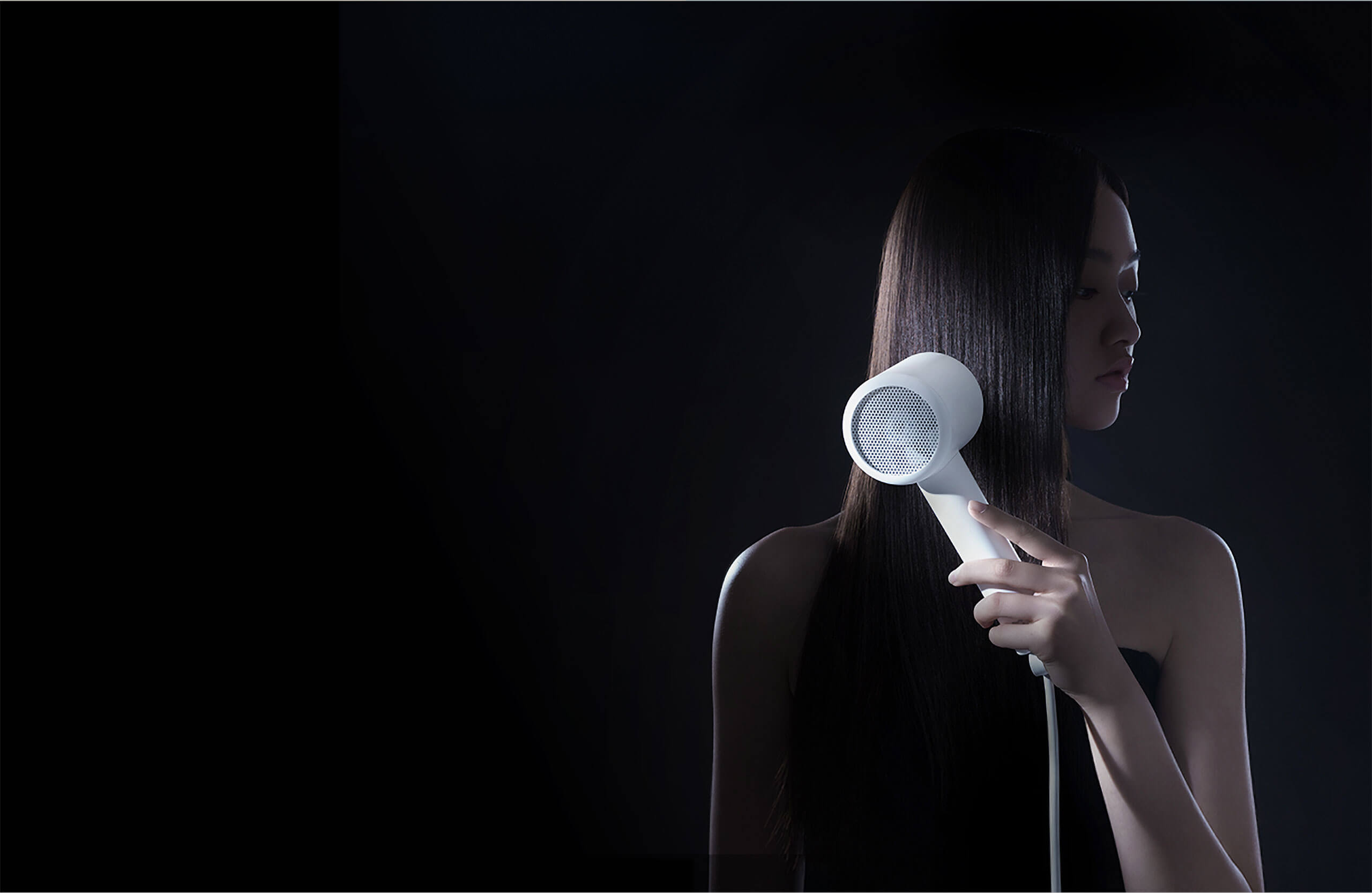 Xiaomi Mijia H300 Hair Dryer Lifestyle Image Woman holding a white Xiaomi Mijia H300 hair dryer beside her long hair against a dark background