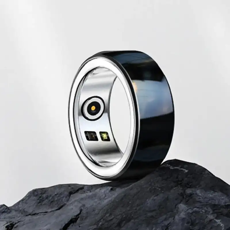 Black Smart Ring – Interior Sensor Close-Up Black smart ring with a silver interior and visible sensors displayed on a dark rock