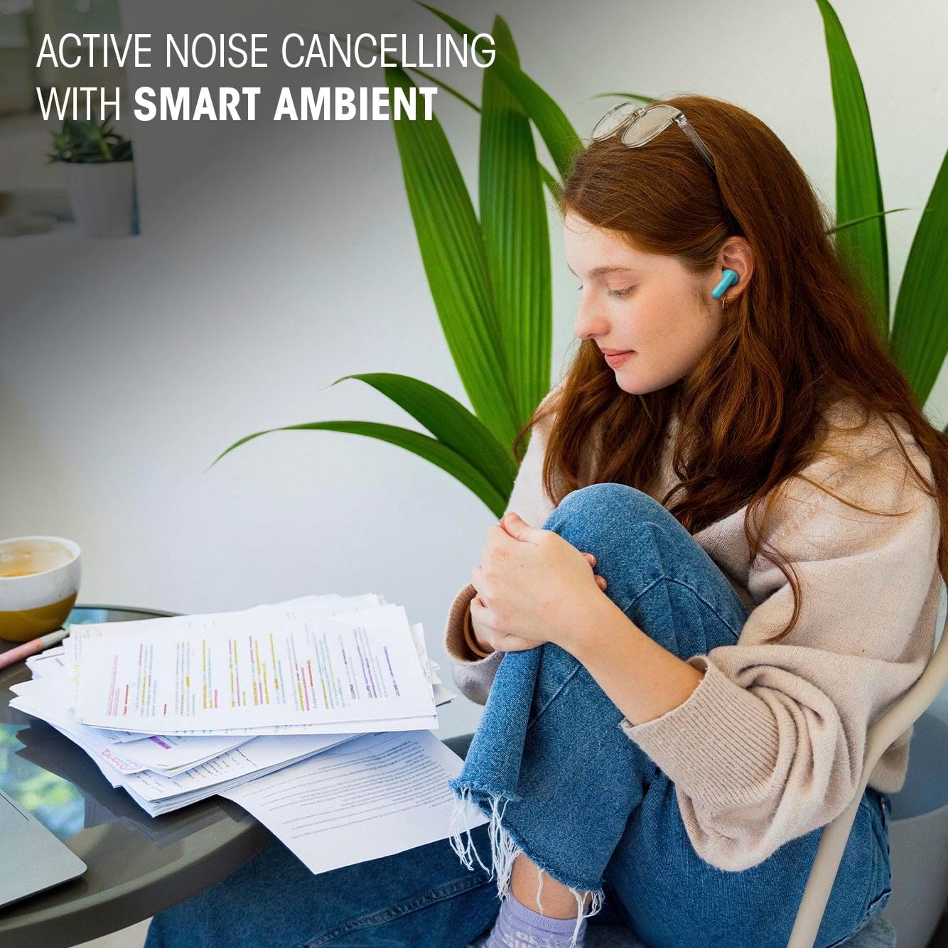 Wireless Earbuds Active Noise Cancelling Study Display Woman wearing a turquoise wireless earbud while reviewing study notes at a table