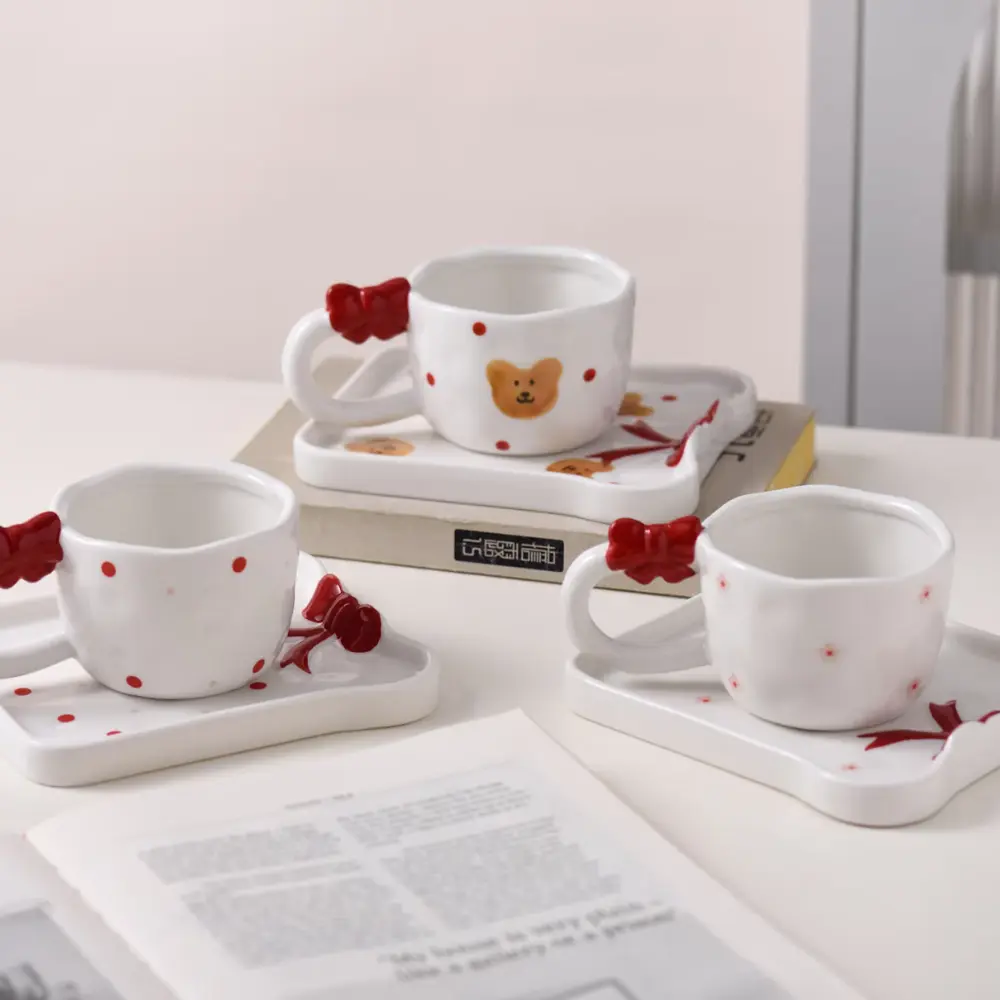 Red Bow Cup and Tray Set Collection Three white cup and tray sets with red bows in bear-pattern and polka-dot designs