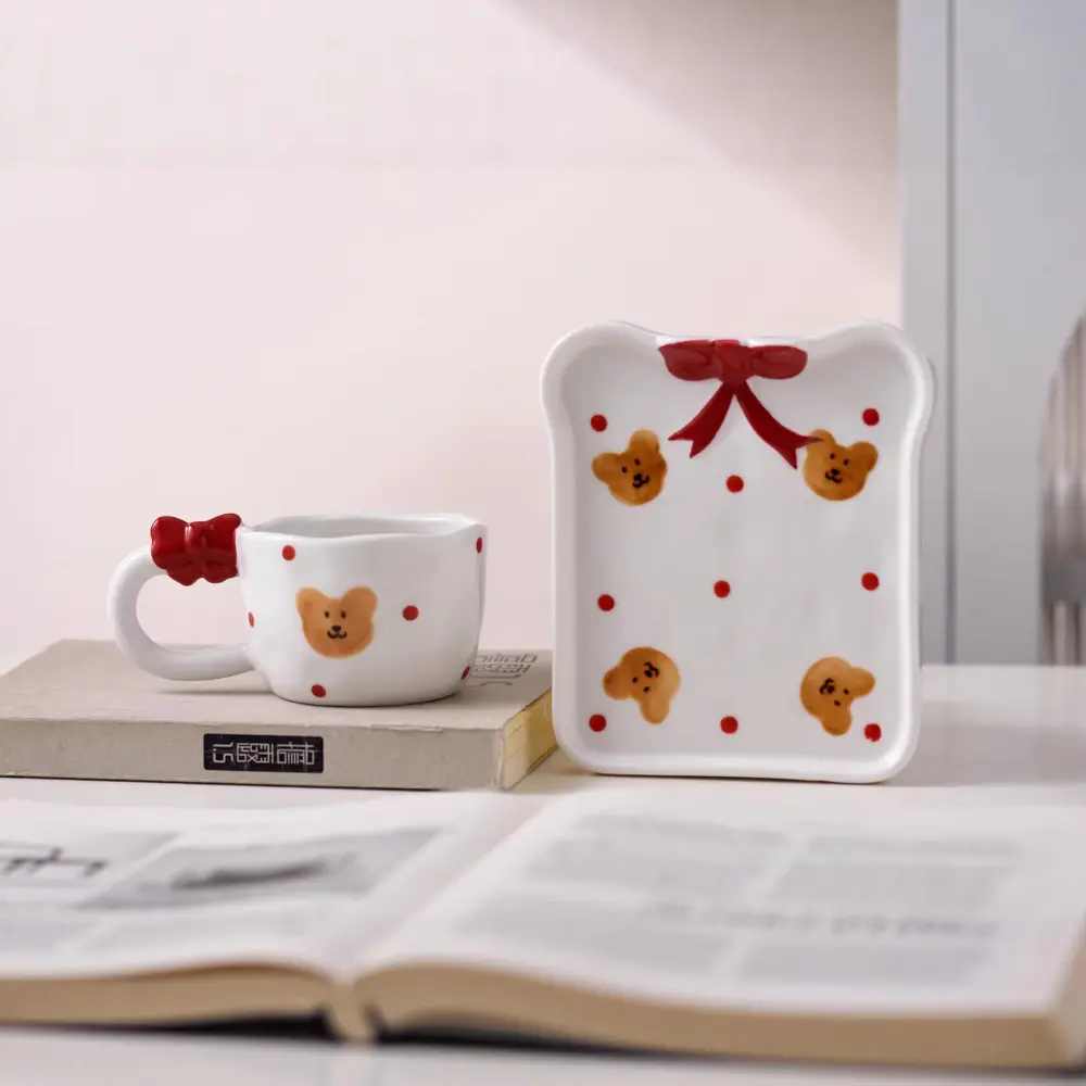 Bow and Bear Cup Set with Upright Tray Bear-pattern cup on a closed book beside an upright matching tray with red bow decoration